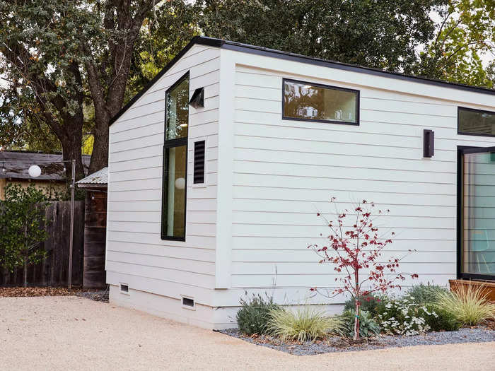 The ADU has a white facade with black trim, which fits the style of the area.