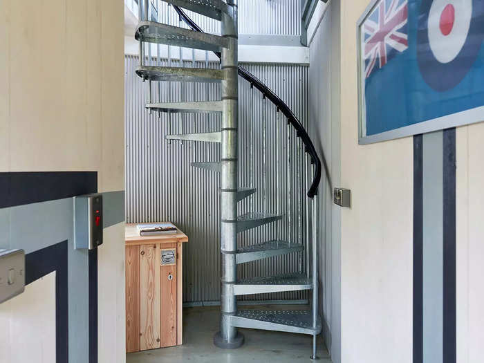 A metal spiral staircase leads up to the kitchen, lounge, and wrap-around balcony.