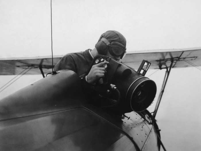 By 1935, the technology had developed further. Cameras were now used on planes. Here, an airman uses a rapid-action, automatic aerial camera while flying. It could be used for vertical or oblique shots.