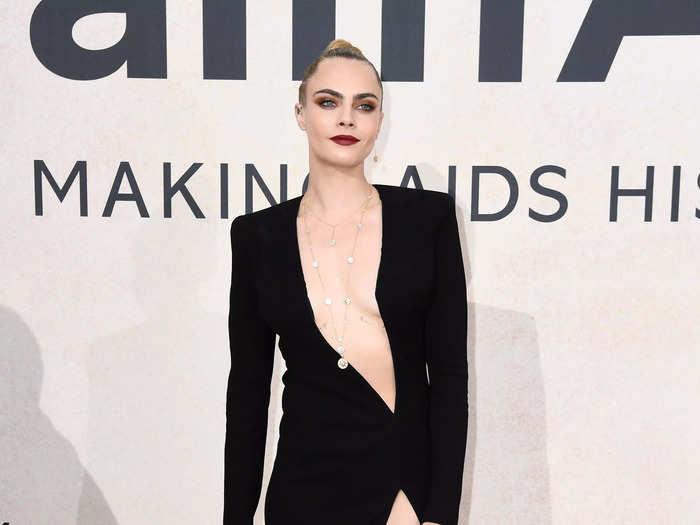 At another Cannes event, Delevingne wore a long-sleeved black gown with a neckline reaching her left hip. A slit ran up the same side.