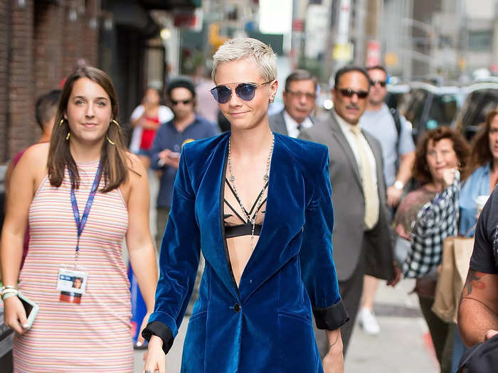 Delevingne wore a strappy black bra under a blue velvet suit in July 2017.