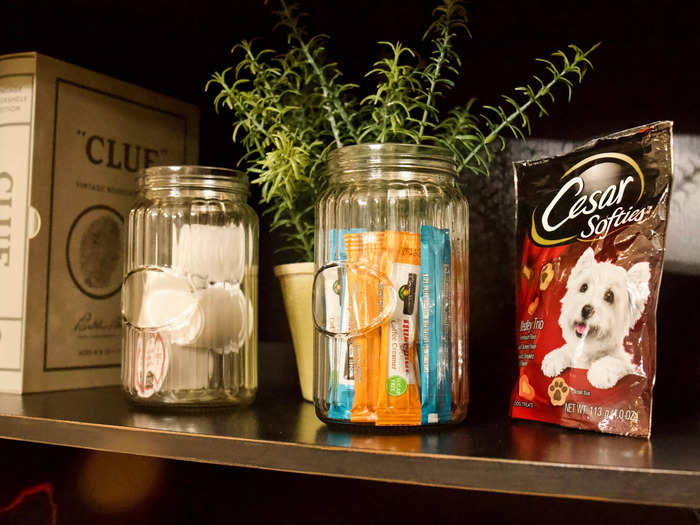 An armoire next to the bed held a variety of items, including a microwave, dog treats, and board games.