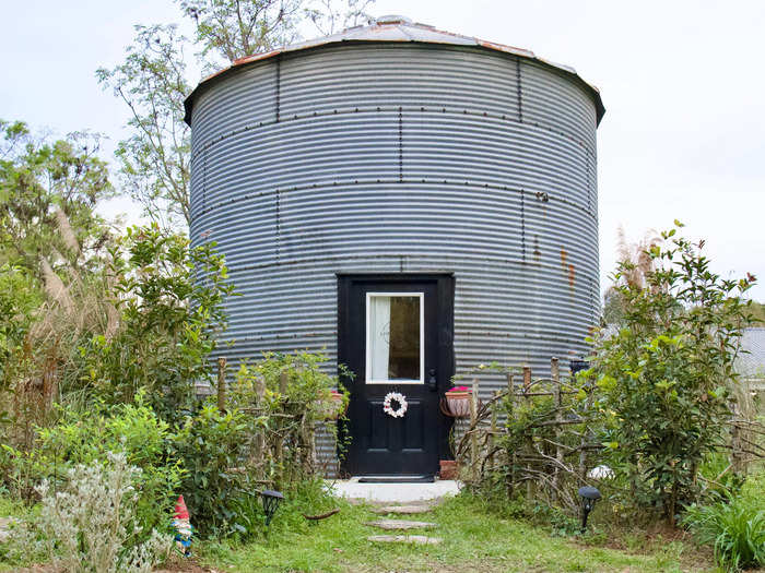 The bin was surrounded by plants and garden decor, and had a small concrete patio with two chairs.