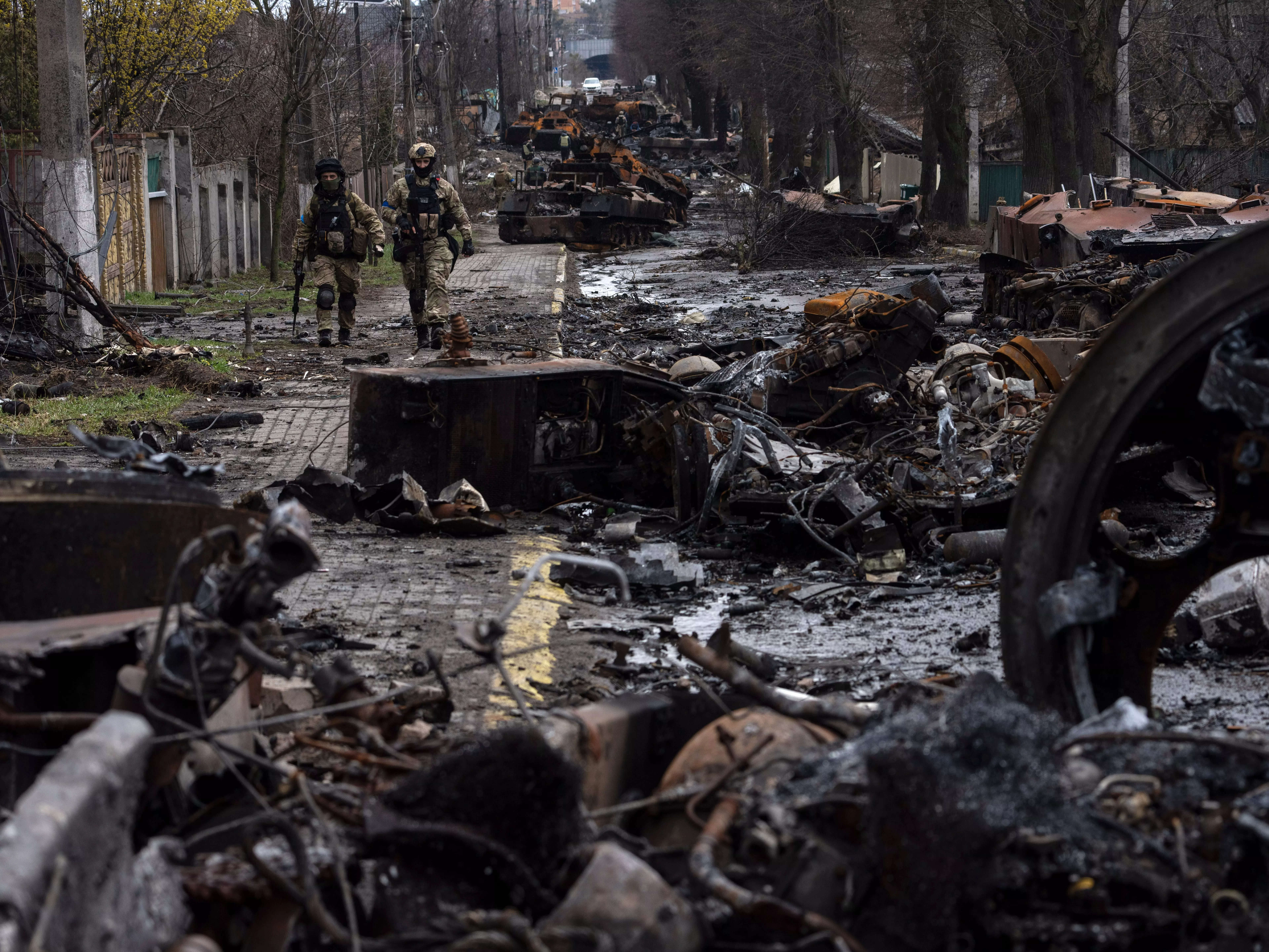 Soldiers walk amid destroyed Russian tanks in Bucha.