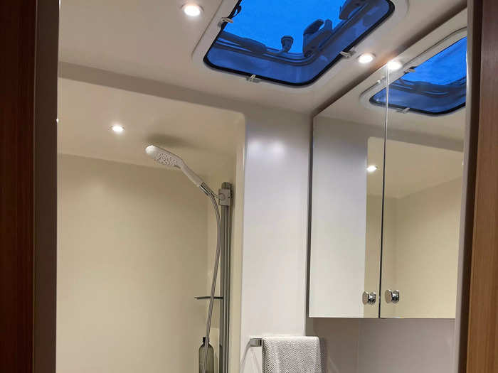 The L-shaped bathroom, which is right behind the kitchen, has a corner toilet, sink and spacious shower. A roof window brings in even more light.