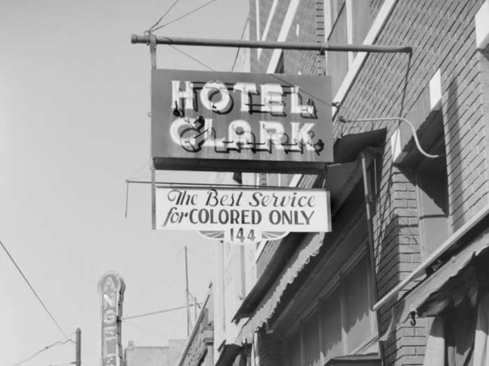 Discriminatory laws and practices, including Black travelers being denied access to services like gas, food, restrooms, and lodging, as well as unreasonable police stops, made driving solo a hazardous experience.