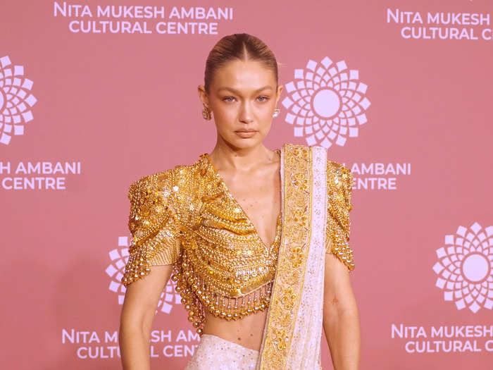 Gigi Hadid donned a two-piece gold and ivory sari and accessorized it with gold jewelry.