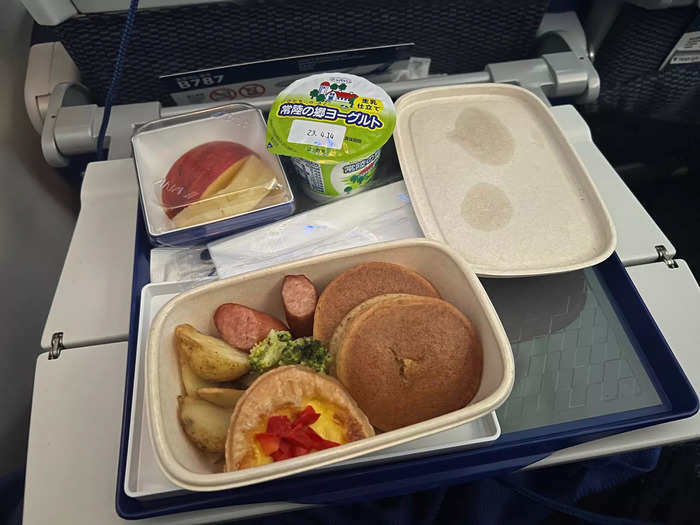 Around three hours from landing, we were served breakfast. The options were fish or pancakes — I opted for the latter, which came with syrup-filled pancakes, potatoes, broccoli, sausage, egg, fruit, and yogurt.