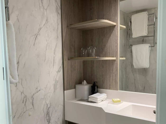 The marble walls, wood shelving, and well-lit mirror really helped make this bathroom feel like one from a luxury resort.