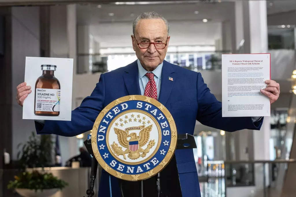 US.. Senator Charles Schumer holding photos of a bottle with drug Xylazine in right hand and letter issued by Drug Enforcement Administration (DEA) alerting of threat as fentanyl is mixed with Xylazine in left hand.